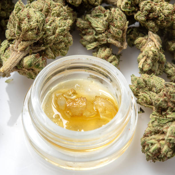 Jar of cannabis concentrate surrounded by flower