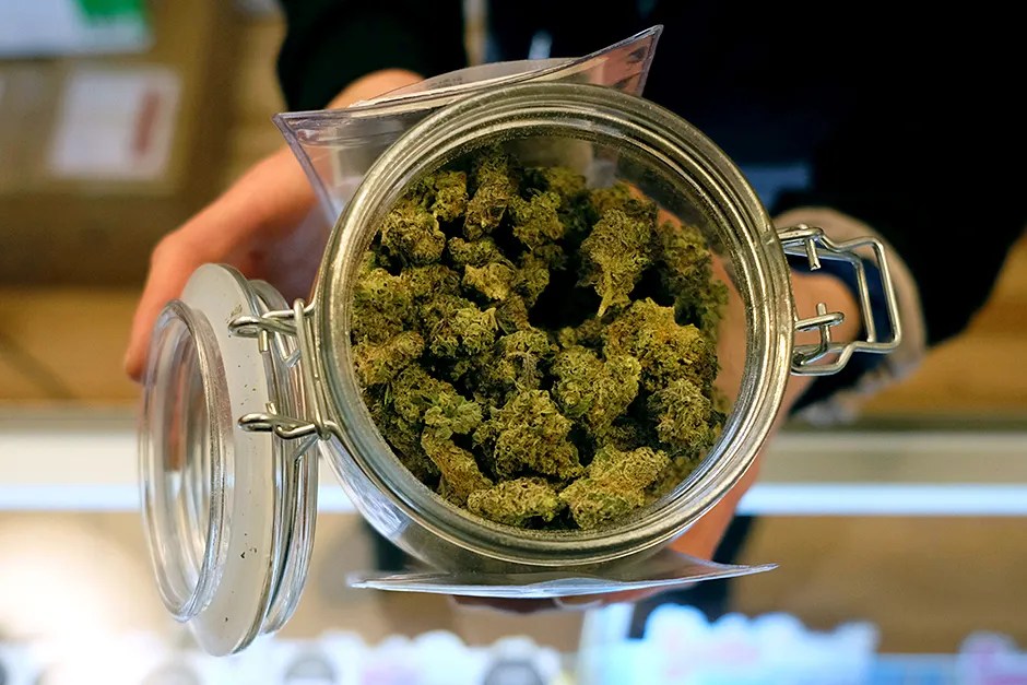 Jar of cannabis flower held over a counter