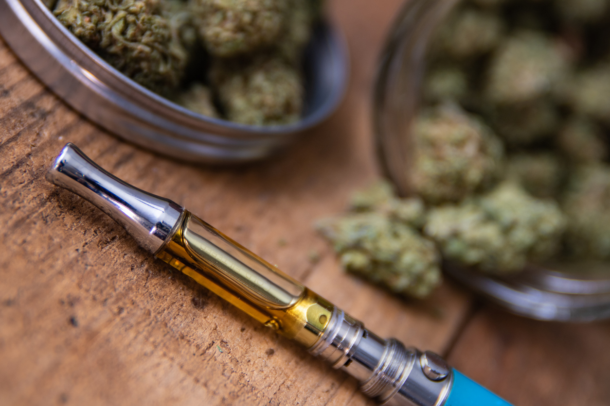 Vape cartridge beside a jar of flower
