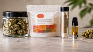 Cannabis flower in a glass jar, a pouch of gummies, a pre-roll tube and a vape cartridge lined up on a counter