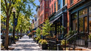 Illustration of a tree-lined Washington DC street with brick rowhouse storefronts and steps down to lower-level shops